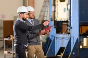 two people wearing white hardhats in an industrial setting.